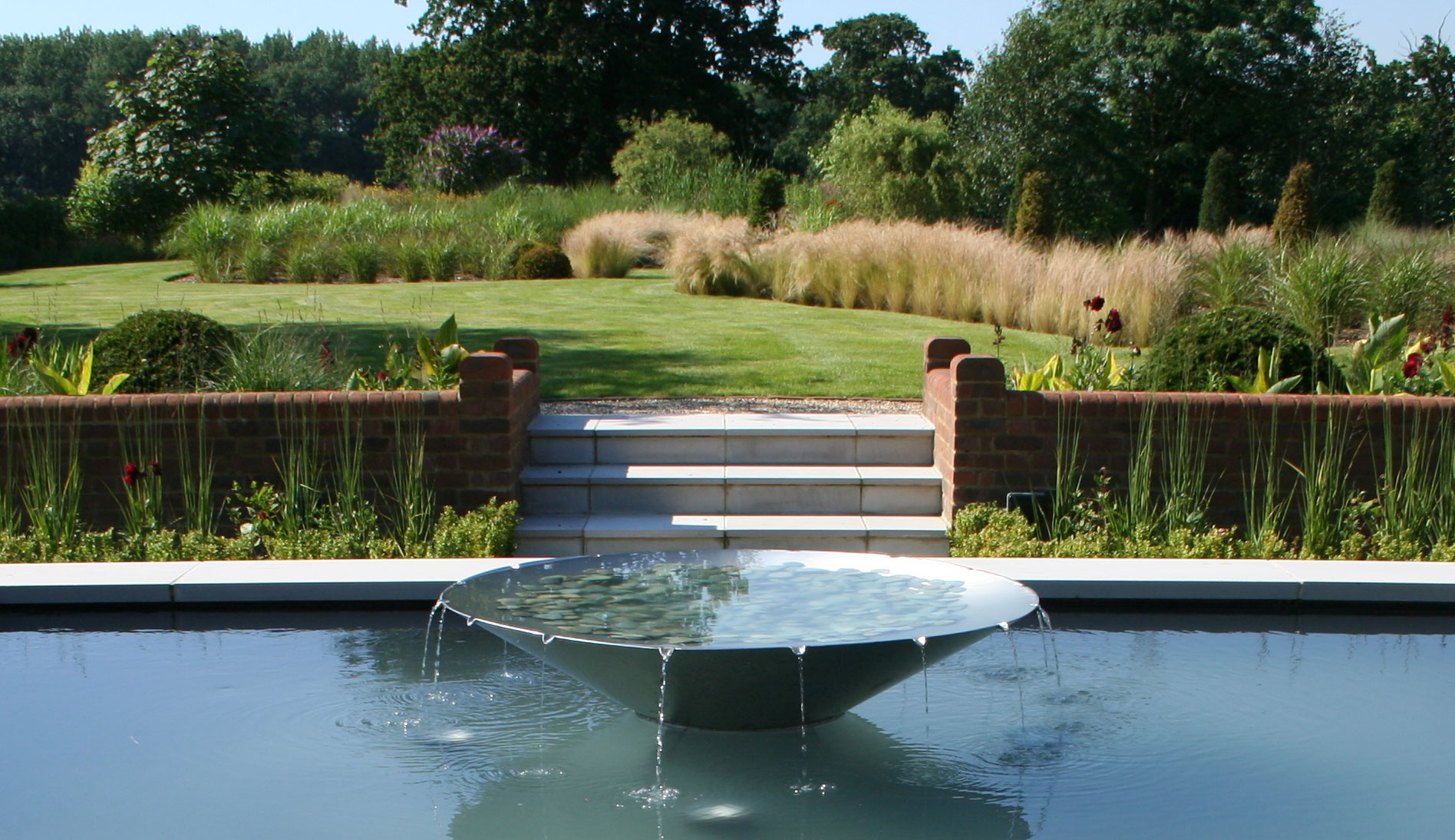 Garden of spiral grass borders designed by Peter Eustance  Water feature terrace
